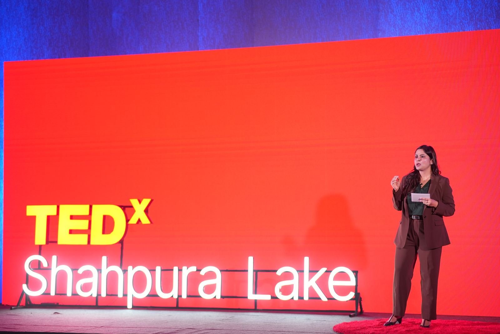 Host on the red TEDxShahpura Lake stage